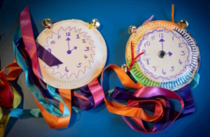 Paper plates with hand-drawn clock faces and colourful ribbons