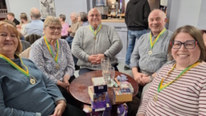 The 5 members of the winning Quiz Night team with big smiles and first place medallions