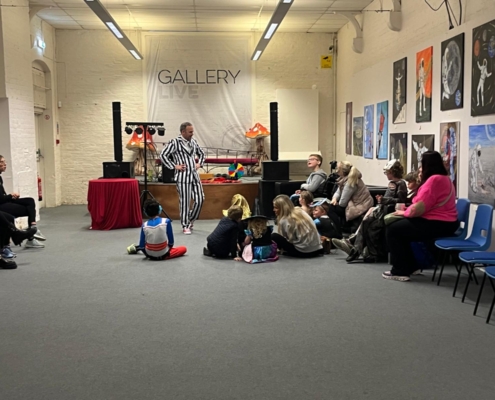 The children's entertainer has the children sit on the floor